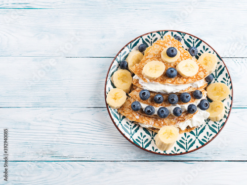 Christmas tree shaped sweet crepes with cream greek yogurt and blueberries on white wooden table. photo