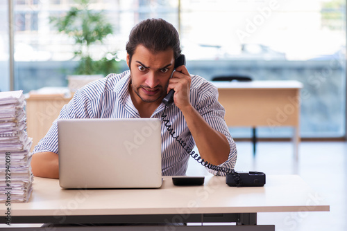 Young male employee unhappy with excessive work in the office