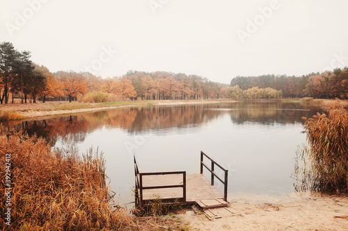 Wooden pier and autumn trees on lake. Autumn background