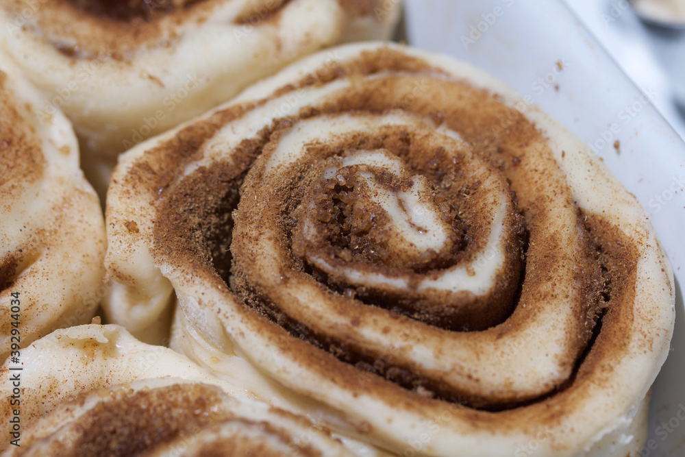 Baking cinnabons. The cinnamon dough is in the baking dish. Close-up shot. Baking cinnabons. The cinnamon dough is in the baking dish. Close-up shot.