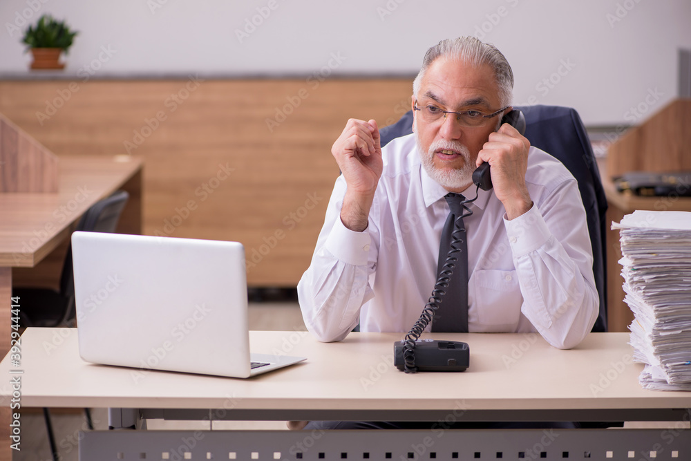 Old male employee unhappy with excessive work in the office Old male employee unhappy with excessive work in the office