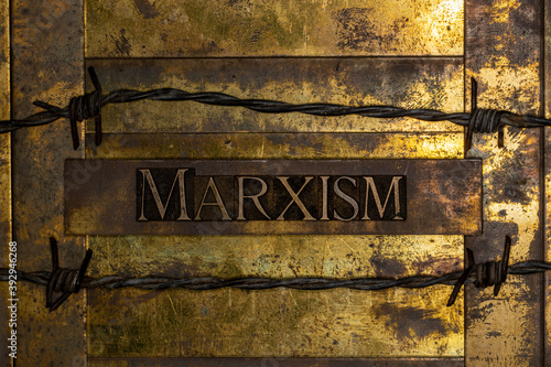 Marxism text on vintage textured grunge copper and gold background lined with barbed wire photo