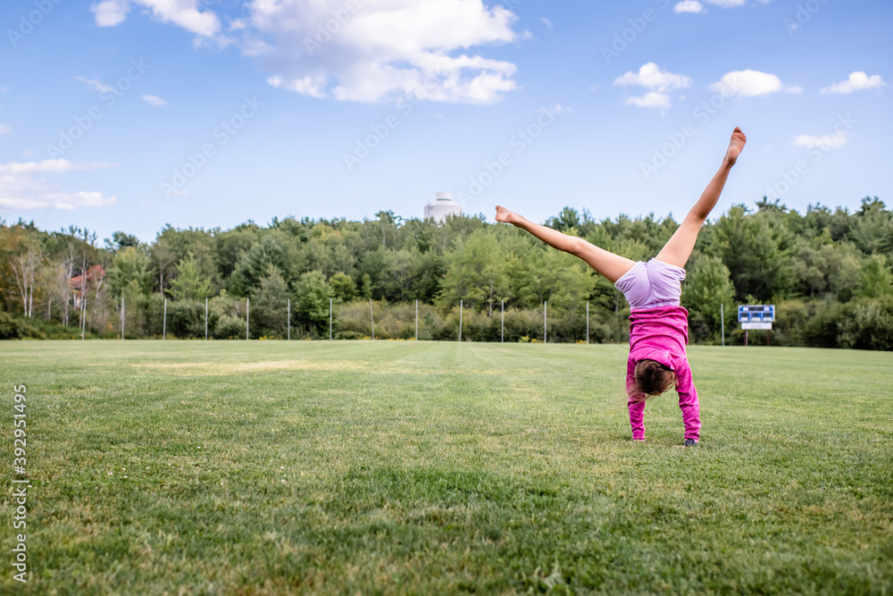 child doing cartwheel in field child doing cartwheel in field