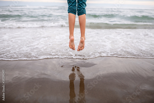 girl jumps over waves with pointed toes photo