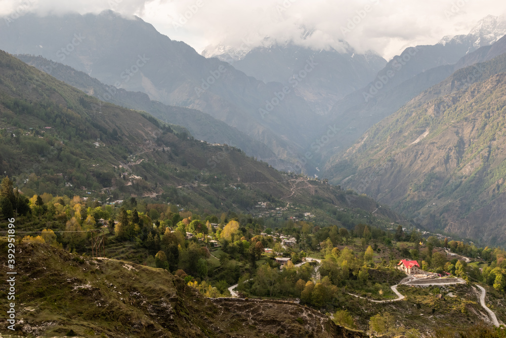Clouds covering a Himalayan mountain peak rising above a green valley in the village of Munsyari in Uttarakhand.