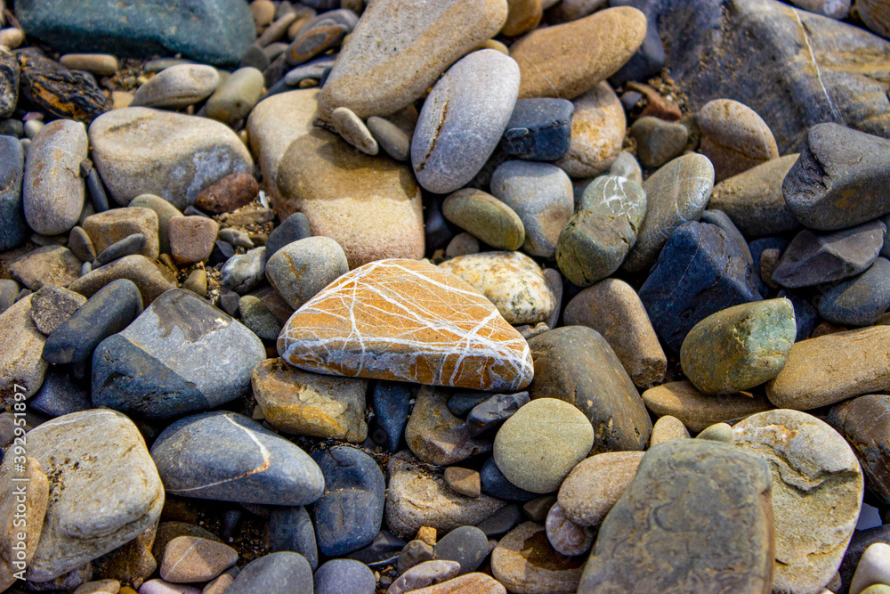 Pebble beach. Beautiful sea stones, different sizes and textures. With streaks, inclusions. On the beach after the storm, small objects and shell fragments were thrown out. Textured rocky background. Pebble beach. Beautiful sea stones, different sizes and textures. With streaks, inclusions. On the beach after the storm, small objects and shell fragments were thrown out. Textured rocky background.