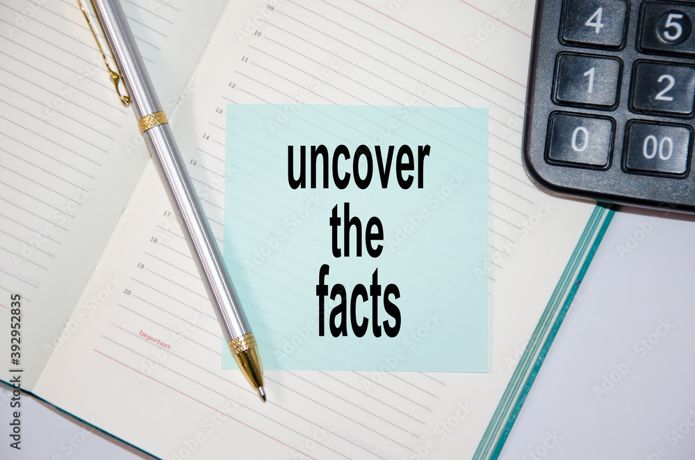text uncover the facts written on a blue sticker glued to a notebook next to a calculator and a pen text uncover the facts written on a blue sticker glued to a notebook next to a calculator and a pen