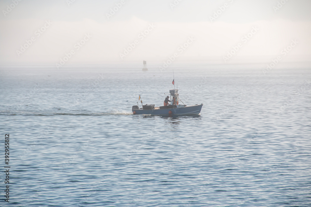 Fisherman’s boat going across the ocean on a foggy day