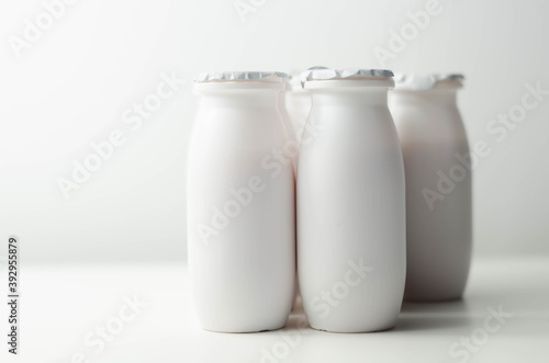 White plastic yogurt bottles on white background, typical packaging for dairy products