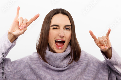 Young beautiful girl wearing casual purple sweater standing over isolated white background shouting with crazy expression doing rock symbol with hands up. Music star. Heavy music concept.