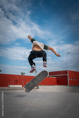 
joven hace un truco llamado heelflip en un parque de patinaje. composición vertical photo