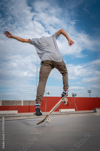 
joven hace un truco llamado kickflip en un parque de patinaje. composición vertical photo