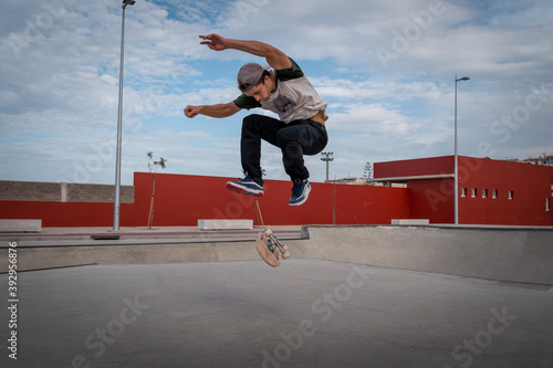 
joven hace un truco llamado varial flip en un parque de patinaje. photo