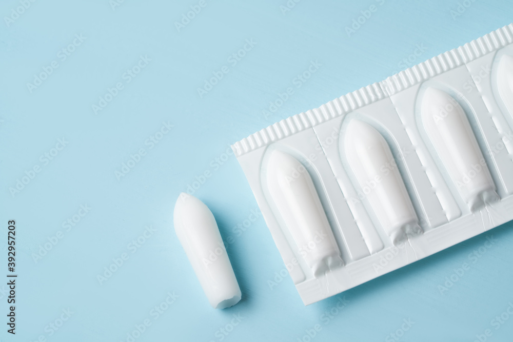 Suppository for anal or vaginal use on a blue background. Candles for treatment of hemorrhoids, temperature, thrush, inflammation.