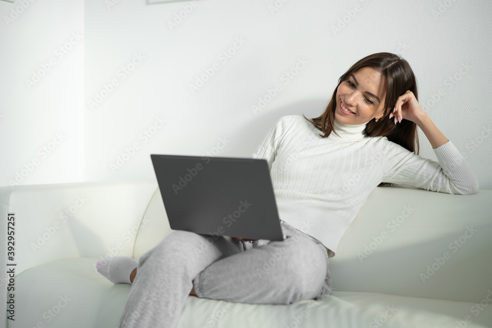 Young woman sitting on sofa and using laptop for work. Young woman sitting on sofa and using laptop for work.