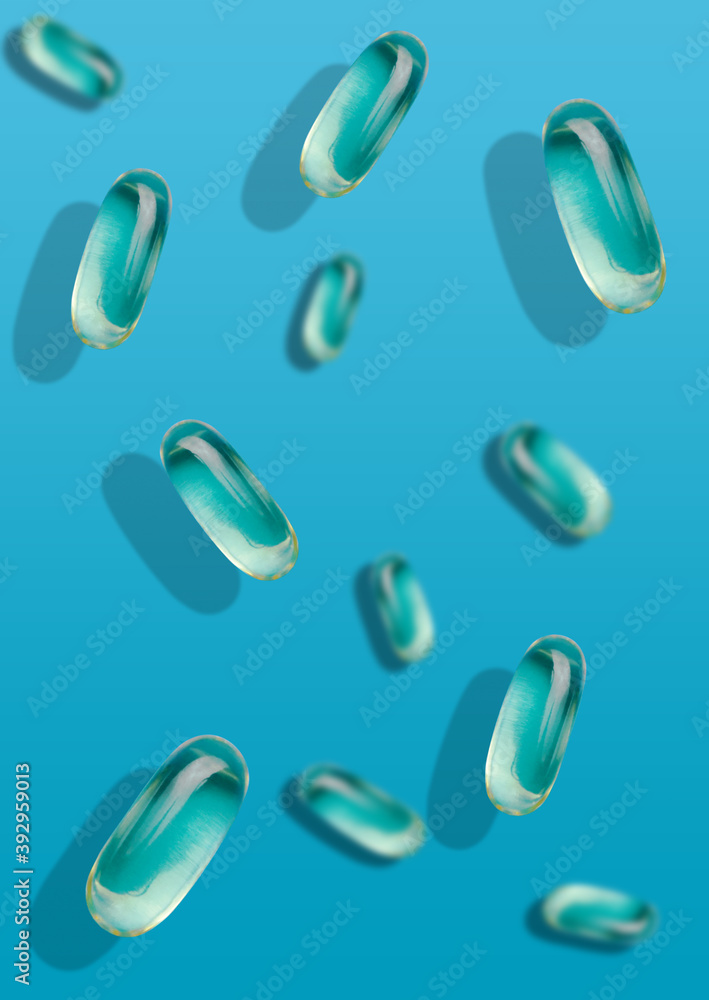 Falling transparent fish oil pills on different planes against a blue uniform background. Vitamins and pills.