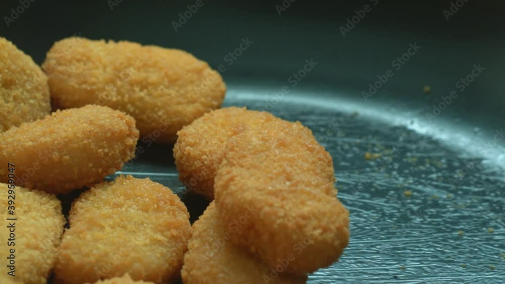 Close-up of an unidentified man stirs golden chicken nuggets fried in a pan. The concept of delicious and healthy gourmet food. Slow motion