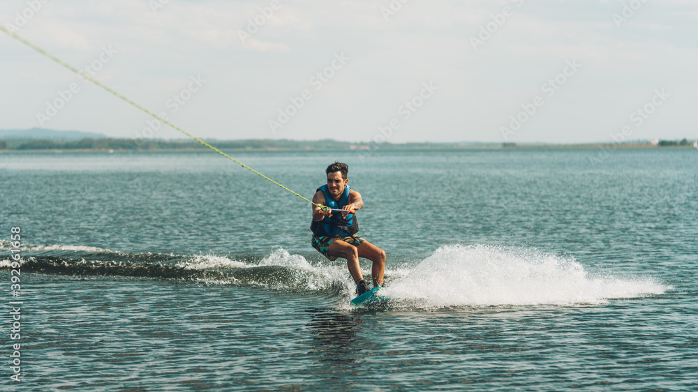 young man doing wakeboarding in a lake whit mountains also doing jumps