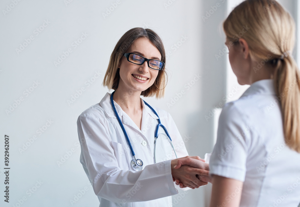 woman doctor shakes hands with patient in white t-shirt woman doctor shakes hands with patient in white t-shirt