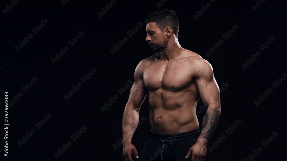Fototapeta premium Fit and sporty bodybuilder over black background. Sportsman in studio. Sport and fitness concepts.