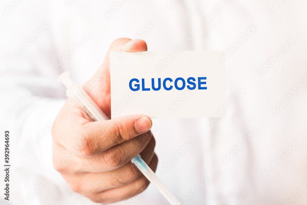 Word glucose on a white background with a syringe in hand. Medicine concept