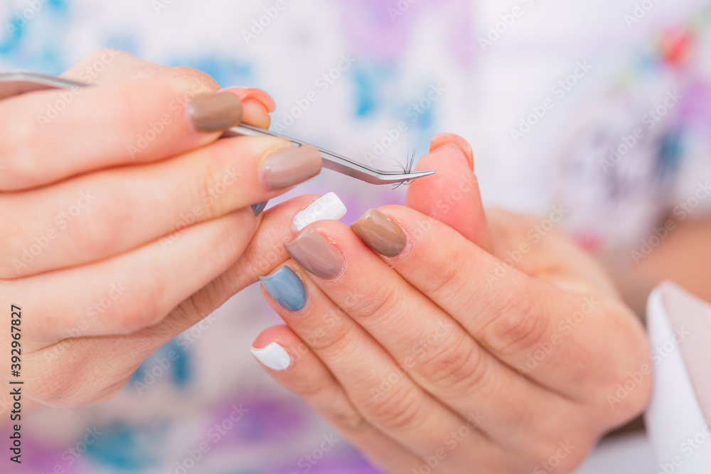 Cosmetologist holding a tweezer with false eyelashes - Procedure of placing false eyelashes hair by hair. Cosmetologist holding a tweezer with false eyelashes - Procedure of placing false eyelashes hair by hair.