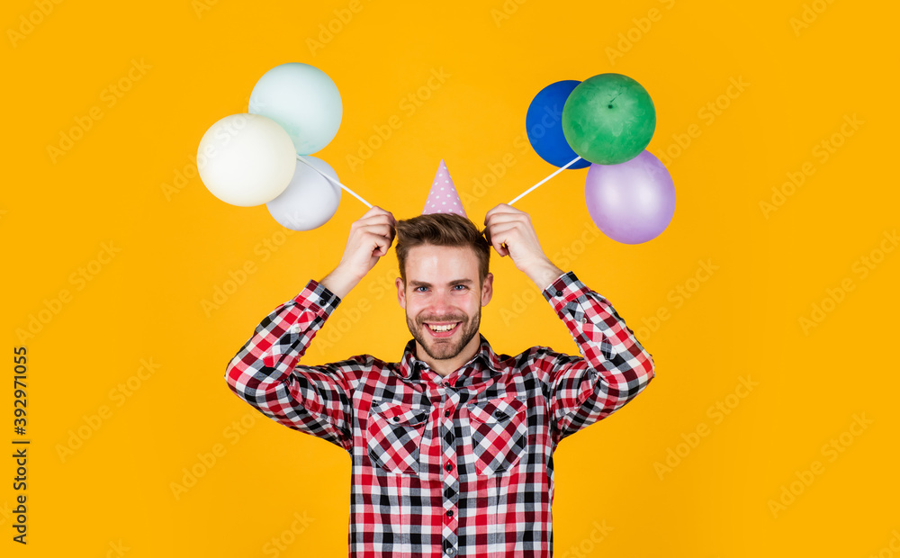 Fototapeta premium pure party goer. funny man in birthday cap. guy hold festive balloons. happy holiday celebration. time for fun and presents. happy birthday or anniversary. feel cheer and joy
