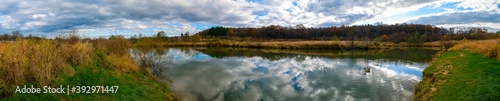 Panoramic landscape from the shore of the lake with colorful clouds and a swan in autumn