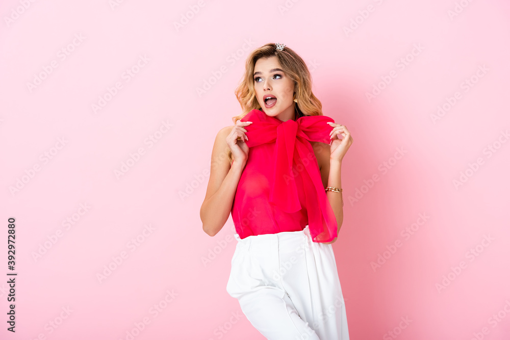 elegant woman in crown showing bow on pink background elegant woman in crown showing bow on pink background