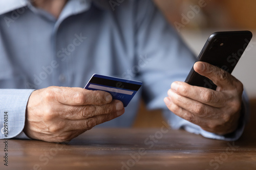 Close up senior man holding smartphone and plastic credit or debit card, mature customer paying online in store, entering information, browsing banking service, making secure internet payment © fizkes
