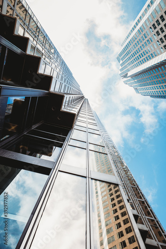 Canvas Print Looking up at the blue sky with skyscrapers and clouds.