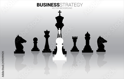 Silhouette of businessman standing on white pawn chess piece in front of all of black chess piece . Concept of underdog business marketing strategy.
