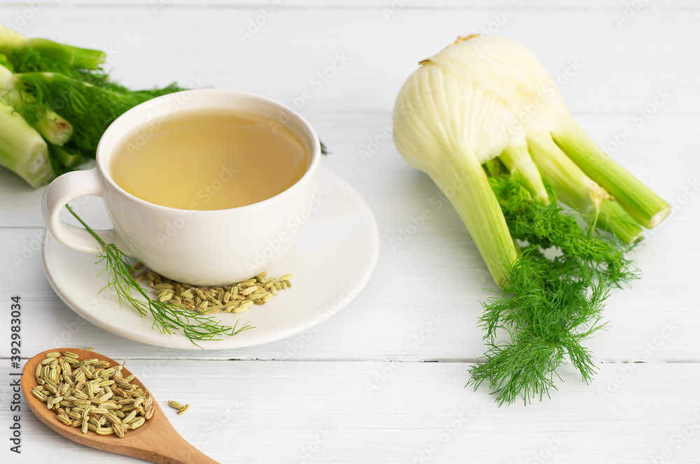 Herbal infusion fennel tea in glass cup or mug with dried fennel seeds and fennel bulbs. Alternative medicine background concept (Foeniculum vulgare) Herbal infusion fennel tea in glass cup or mug with dried fennel seeds and fennel bulbs. Alternative medicine background concept (Foeniculum vulgare)