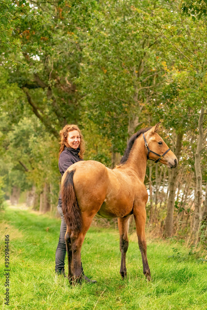 A light brown buckskin foal, the female owner stands next to the stallion Autumn Sun A light brown buckskin foal, the female owner stands next to the stallion Autumn Sun