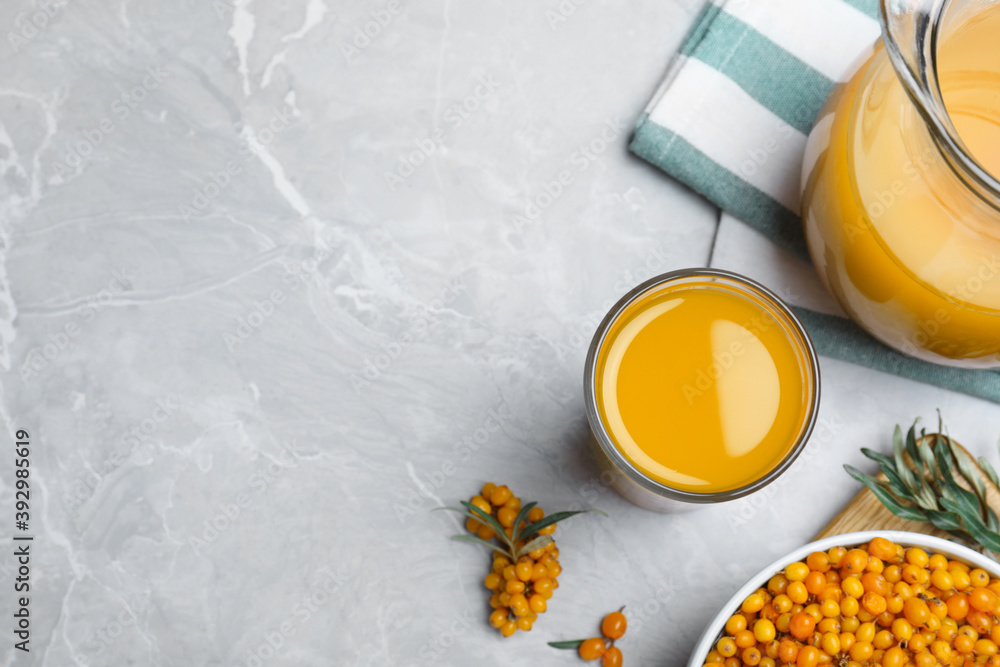 Fototapeta premium Sea buckthorn juice and fresh berries on light marble table, flat lay. Space for text
