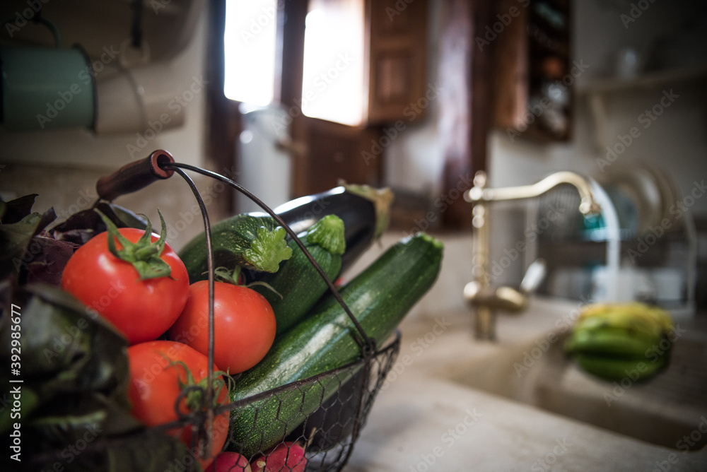 basket of vegetables on top of a kitchen counter and a background wooden window basket of vegetables on top of a kitchen counter and a background wooden window