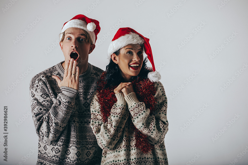 Happy young couple in Santa hats. Christmas couple. Santa hats. Funny face. Family concept. Happy young couple in Santa hats. Christmas couple. Santa hats. Funny face. Family concept.