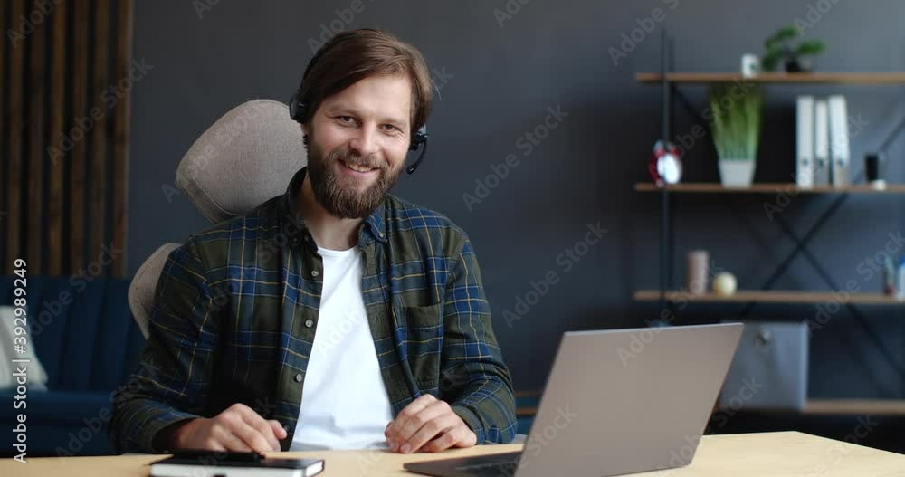 Handsome Operator in Call-Center, Technical Support is working Indoor, smiling at the Camera. Handsome friendly Man is wearing in Headset, using Laptop. Online Job. Working Distantly. Male`s Portrait. Handsome Operator in Call-Center, Technical Support is working Indoor, smiling at the Camera. Handsome friendly Man is wearing in Headset, using Laptop. Online Job. Working Distantly. Male`s Portrait.