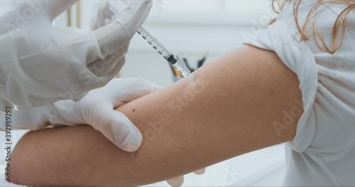Close up shot of doctor injecting vaccine to female hand, flu and coronavirus prevention photo