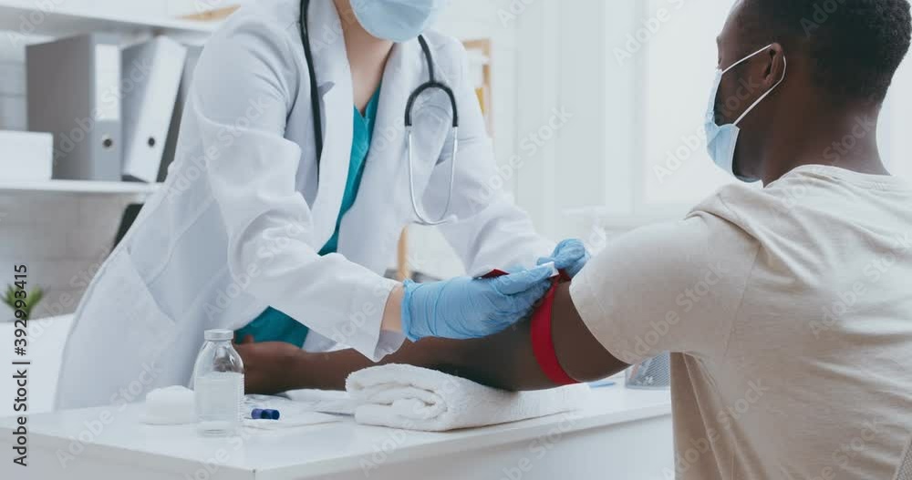 Intravenous medical research. Doctor applying tourniquet on black guy arm before taking blood from vein Intravenous medical research. Doctor applying tourniquet on black guy arm before taking blood from vein