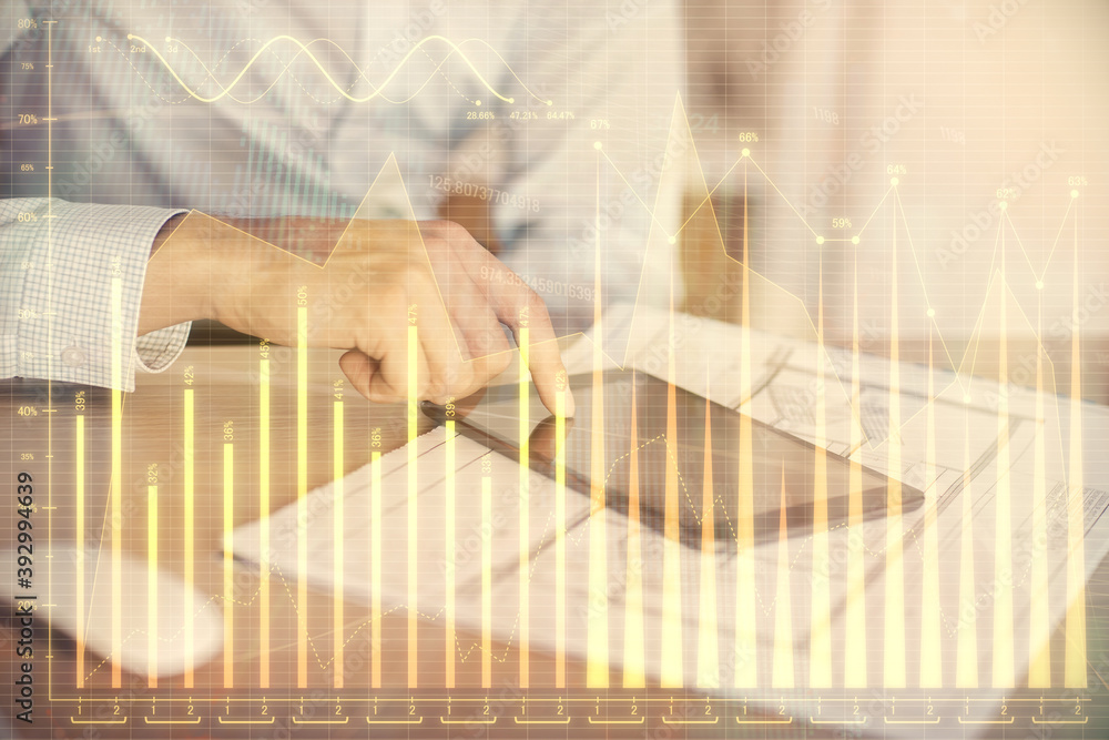 Double exposure of man's hands holding and using a digital device and forex graph drawing. Financial market concept.