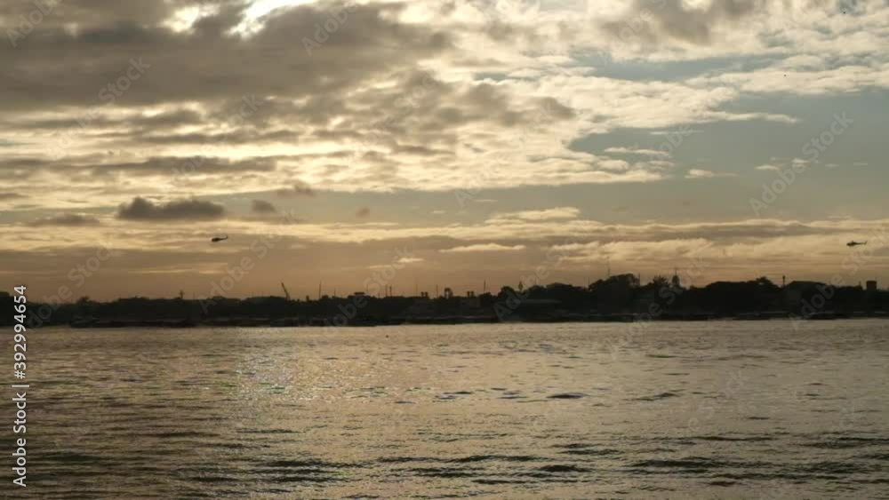 Two Helicopters flying over a city during a beautiful sunrise facing the sea in the Philippines. No people. Two Helicopters flying over a city during a beautiful sunrise facing the sea in the Philippines. No people.