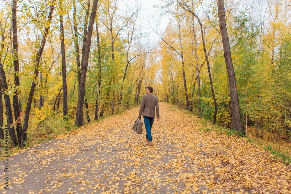 Tall handsome man with a bag on the autumn alley Tall handsome man with a bag on the autumn alley