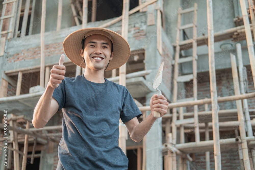 The mason wears a smiling cap with a thumbs up and holds a cement taper to the workplace
