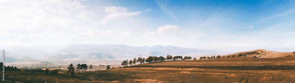 Obraz premium Georgian autumn landscape web banner. Sunny and bright November with trees and foggy mountains over horizon. Great for website banner advertisements