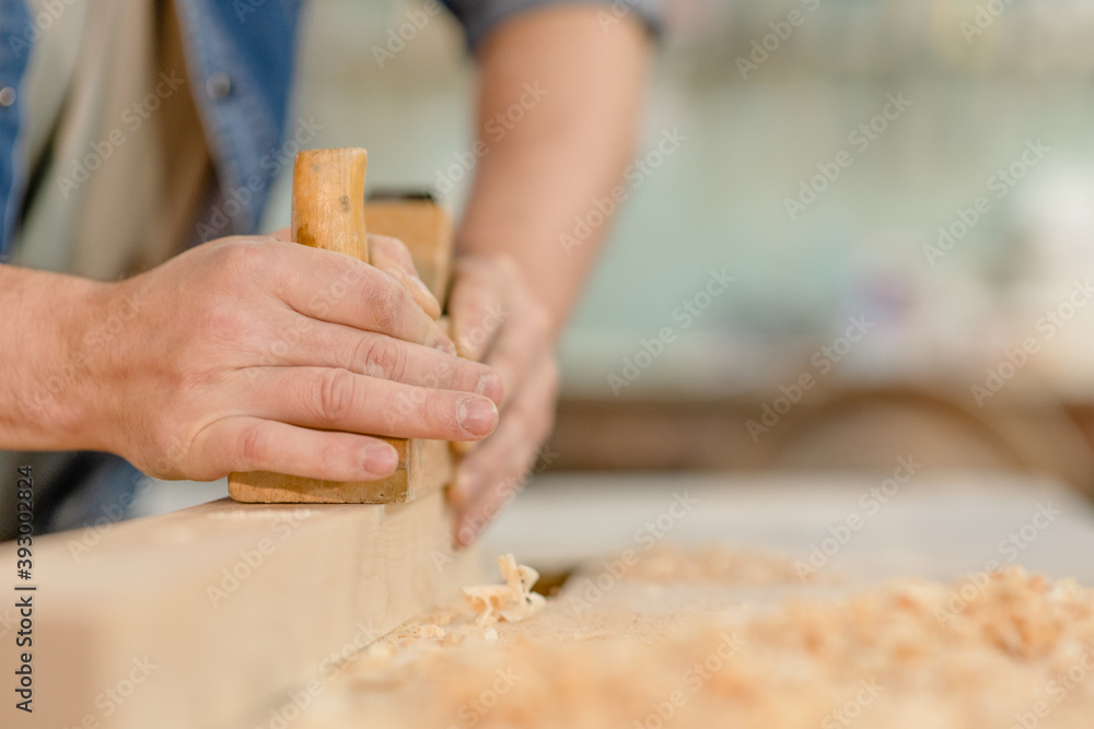 Hands of a carpenter planed wood in a workshop. Empty space for text Hands of a carpenter planed wood in a workshop. Empty space for text