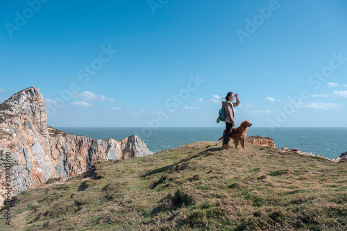 Fototapeta Golden Retriever and owner on a hilltop by the sea