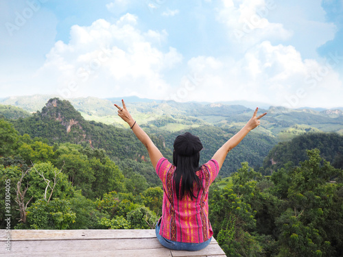 woman tourist raise arms over rainforest mountain and blue sky background.