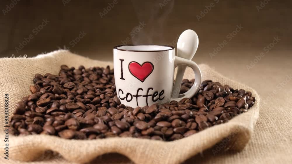 Coffee hot steaming on I LOVE COFFEE cup. Jute background and coffee beans Coffee hot steaming on I LOVE COFFEE cup. Jute background and coffee beans