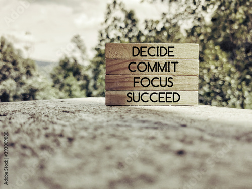 Inspirational words of decide commit focus succeed on wooden blocks background. Stock photo.